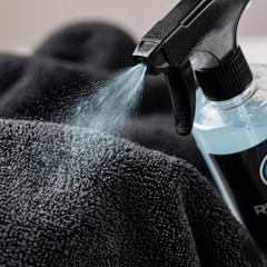 Nettoyant APC Ultra Refresh Cars 500ml pulvérisant un produit bleu sur un chiffon microfibre gris