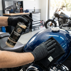 Cera líquida de carnauba Refresh Cars encerando el depósito azul de una moto con paño