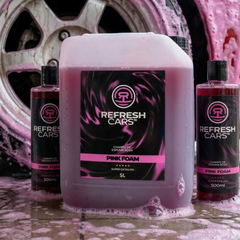 Champú de espuma rosa Refresh Cars rodeado de espuma junto a llanta enjabonada en el lavado del coche