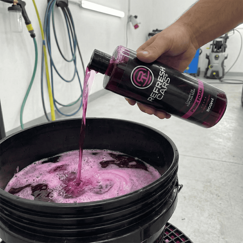 Champú de espuma rosa Refresh Cars vertido desde el bote al cubo de lavado del coche