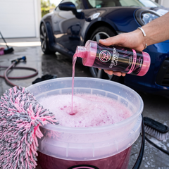 Champú prelavado Refresh Cars vertido en cubo con espuma junto a deportivo azul y guante de lavado