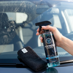 Limpia cristales Refresh Cars pulverizado sobre el parabrisas al sol con bayeta de microfibra
